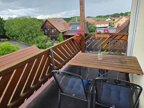 a wooden table and two chairs on a balcony at Service Appartement Weigl in Nittenau