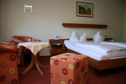 a hotel room with two beds and a table and a chair at Hotel-Restaurant Kohlenbacher-Hof in Waldkirch