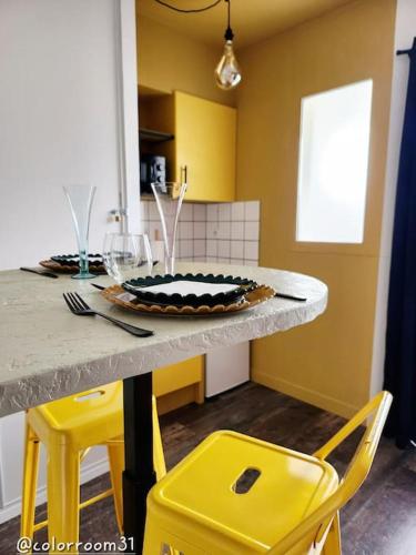 une cuisine avec des chaises jaunes et une table avec une assiette dans l'établissement Colorroom31 - Nuit insolite - Spa - Tantra - Love room, à Rouffiac-Tolosan