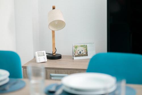 a table with a lamp and two blue chairs at Baltic Apartments in Pobierowo