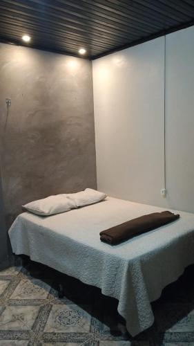 AP 4 - Apartamento Espaçoso, Confortável e Aconchegante - Pousada Paraíso في ماكابا: سرير في غرفة مع جدار