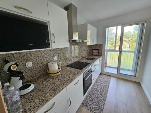 Il comprend une cuisine avec un évier et une télévision murale. dans l'établissement Appartement T3BIS - 74M2, à Marseille