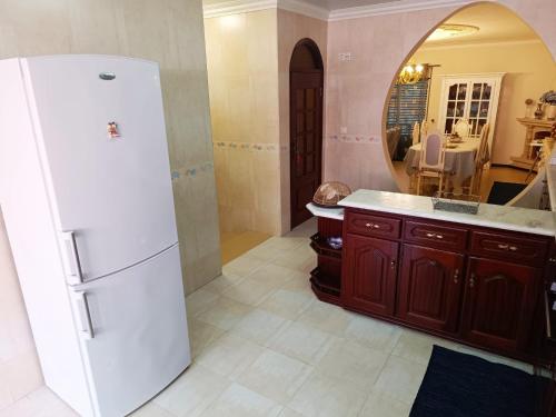 a kitchen with a white refrigerator and a mirror at Caroça House in Nazaré