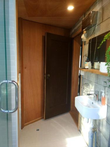 a bathroom with a black door and a sink at Gully hideaway apartment in Hamilton