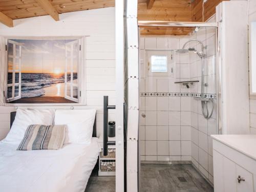 baño blanco con cama y ducha en Rosa's Cottage, garden and free parking, en Zandvoort