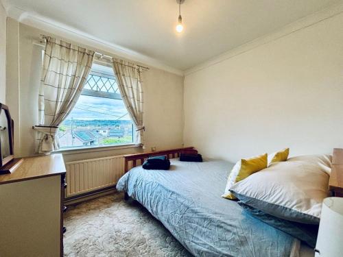 um quarto com uma cama e uma grande janela em EEJs Cozy 2-Bedroom Apartment in Nailsea em Nailsea