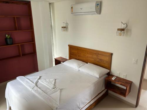 a bedroom with a white bed with a wooden headboard at Apartamento Chique frente ao mar in Flecheiras