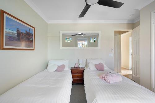 two beds in a room with white walls and pink pillows at Waterfront BNB in Gold Coast