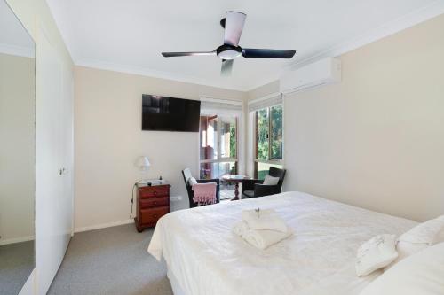 a white bedroom with a bed and a ceiling fan at Waterfront BNB in Gold Coast