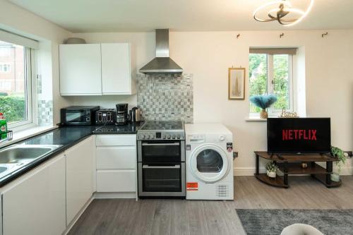 a kitchen with a washing machine and a microwave at Cozy Retreat Near Heathrow Airport in Feltham