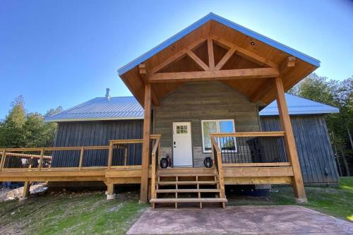 a large wooden cabin with a large deck at Tobermory Village Getaway in Tobermory