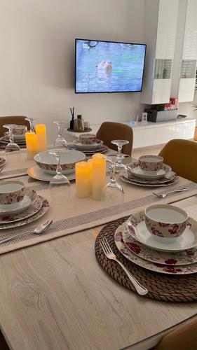 a table with plates and dishes on it with a television at Schöne, ruhige neuwertige 127qm Ferienwohnung in Sidi Daoud