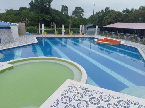 ein großer blauer Pool mit einer Bank daneben in der Unterkunft Hotel Campestre Morichal in Tauramena