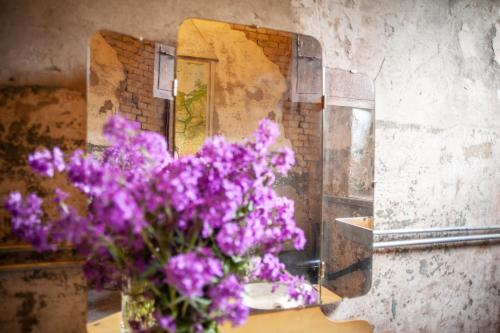 a vase of purple flowers in front of a mirror at CAMP Agroturystyka Gorzelnia Gwieździn in Gwieździn