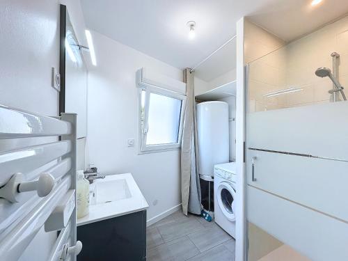 La salle de bains blanche est pourvue d'un évier et d'un réfrigérateur. dans l'établissement Ty Ehanou ravissante maison de vacances, à Landunvez