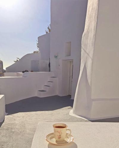 a cup of coffee sitting on a table next to a building at Cave Noelia in Fira
