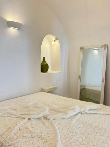 a white bedroom with a bed and a mirror at Cave Noelia in Fira