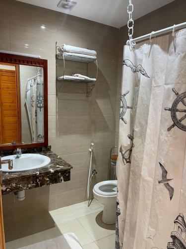 a bathroom with a sink and a toilet and a shower curtain at Palais Benfatah in Marrakesh