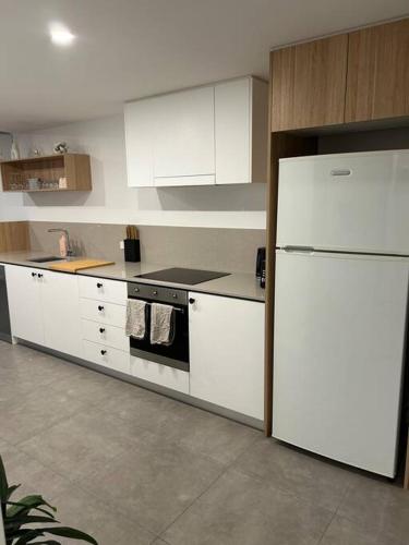 a kitchen with white cabinets and a white refrigerator at 112 at Plush Midnight in Canberra