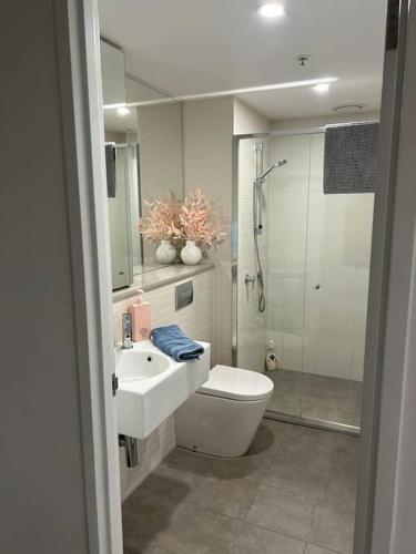 a bathroom with a toilet and a sink and a shower at 112 at Plush Midnight in Canberra