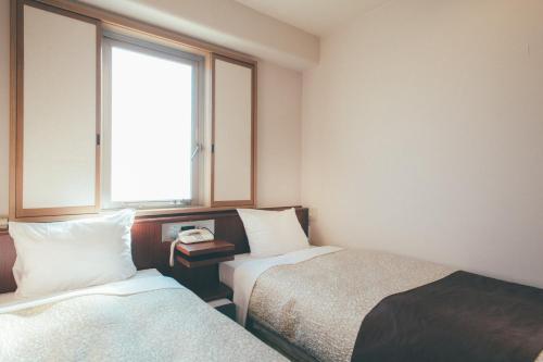 pokój hotelowy z 2 łóżkami i oknem w obiekcie Kuretake-Inn Kakegawa w mieście Kakegawa