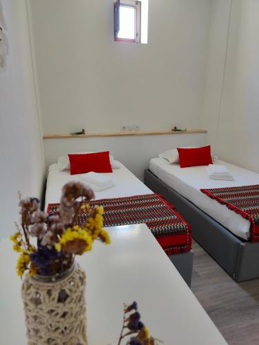 a room with two beds and a vase with flowers at AL Colmeia de Mel in Reguengos de Monsaraz