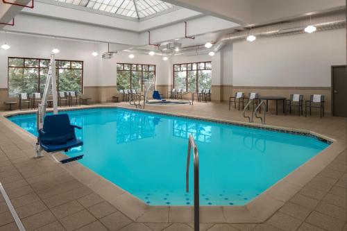 ポートランドにあるレジデンス イン ポートランド ダウンタウン/リバープレイスのテーブルと椅子付きの広い部屋に青い水のプールがあります。
