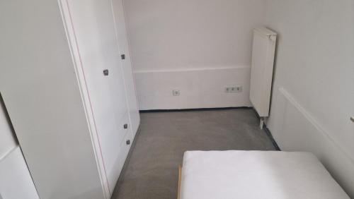 a small white room with a bed and a door at Rooms & Apartments Schwäbisch Gmünd in Schwäbisch Gmünd