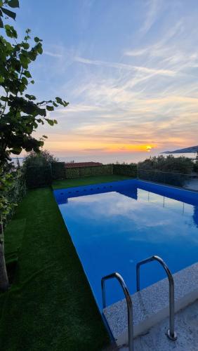 una piscina azul con puesta de sol en el fondo en Villa Skenderi en Sarandë