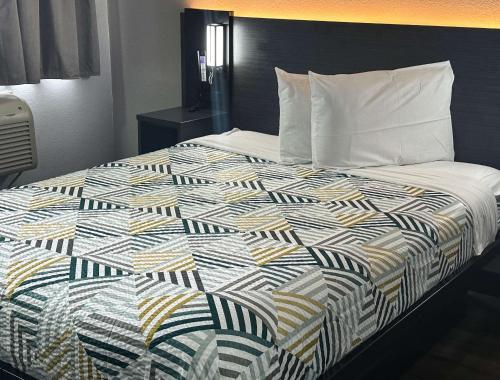 a bed in a hotel room with a colorful quilt at Motel 6-Kissimmee, FL - Orlando in Orlando