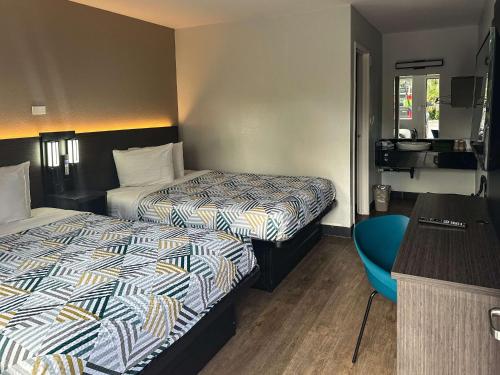 a hotel room with two beds and a desk at Motel 6-Kissimmee, FL - Orlando in Orlando