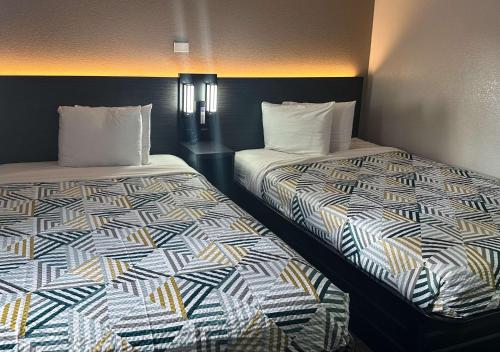 two beds sitting next to each other in a room at Motel 6-Kissimmee, FL - Orlando in Orlando