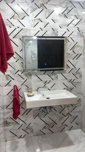a bathroom with a sink and a tv on a wall at Villa Casa Deraoui in Tangier