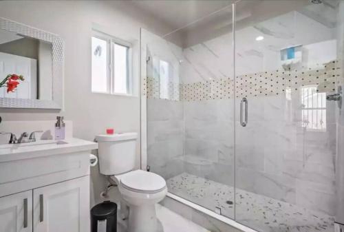 a white bathroom with a toilet and a shower at Spacious family Guesthouse private entry near six flags in Santa Clarita