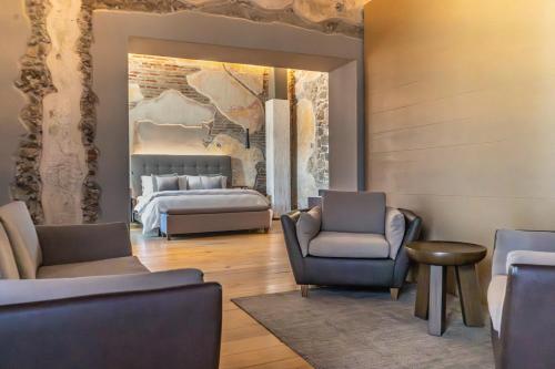 a bedroom with a bed and a couch and chairs at Cartesiano Boutique & Wellness Hotel in Puebla