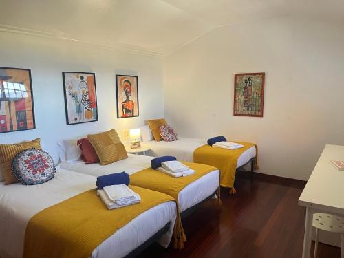 Zimmer mit 3 Betten und gelben Decken in der Unterkunft Casa con piscina, vistas y cerca de las playas in Vigo