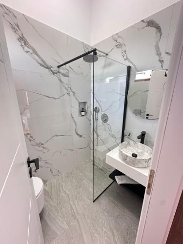 a bathroom with a shower and a toilet and a sink at Elona's Rooms in Krujë