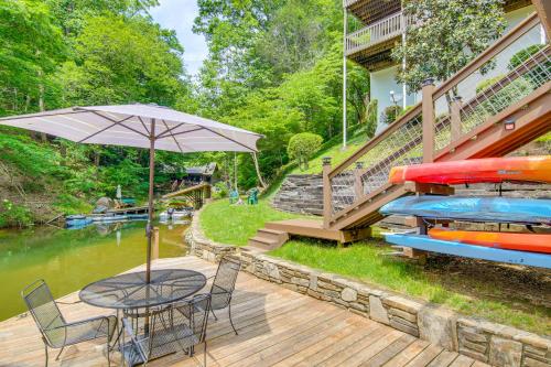 a patio with a table and an umbrella next to a river at 2-Story Deck Waterfront Lake Lure Home! in Lake Lure
