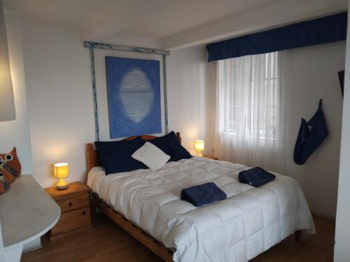 1 dormitorio con 1 cama blanca grande con almohadas azules en Hotel Montealegre, en Valparaíso