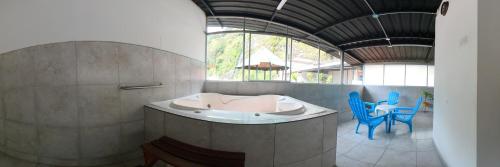 a bathroom with a tub and some blue chairs at Hostal & Spa Casa Real in Baños
