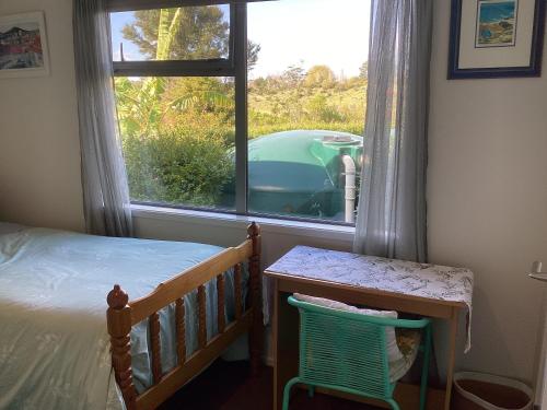 a bedroom with a bed and a window with a car outside at Al Der Rocs B & B in Kerikeri