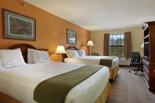 a hotel room with two beds and a television at Days Inn by Wyndham Shallotte in Shallotte