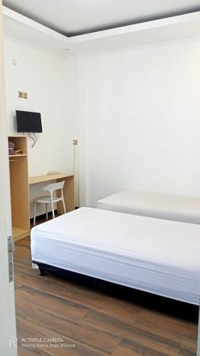 a white bed in a room with a desk at HOMESTAY KIKA SYARIAH PURWOKERTO in Purwokerto