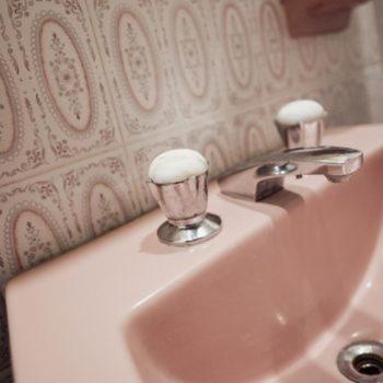 a white sink with two knobs on a wall at Hotel Hey U in Santa Fe