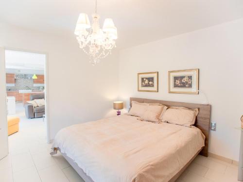 - une chambre blanche avec un lit et un lustre dans l'établissement La petite Sorgues, à Sorgues