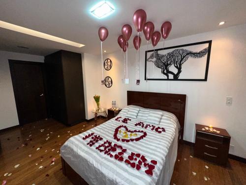 a bedroom with balloons and a bed with a bedspread with a cake at Five Stars Suites - Park - Quito in Quito
