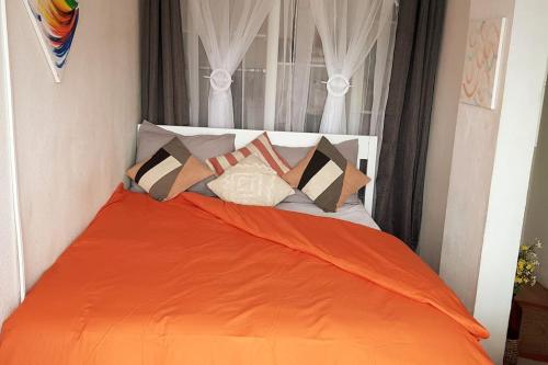 - un lit avec une couverture orange et des oreillers dans l'établissement La Détente Porte de Paris Stade de France, à Saint-Denis