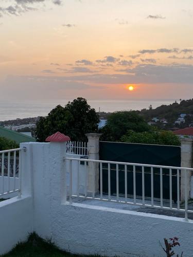 a sunset over the ocean from a white fence at Chalet Paradis in Saint-Claude