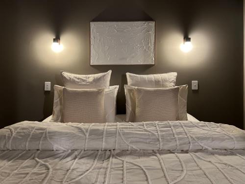 a bed with white sheets and pillows in a bedroom at George - Luxe Residence with Private Rooftop in Adelaide