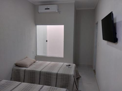 biały pokój z 2 łóżkami i oknem w obiekcie Pousada Luz do Sol w mieście Piranhas